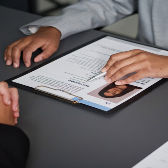 Imagen de un curriculum encima de la mesa con las manos de dos personas